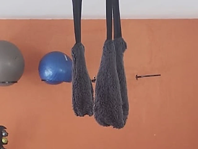 Faixas de suspensão penduradas na barra do teto, em frente à parede laranja
